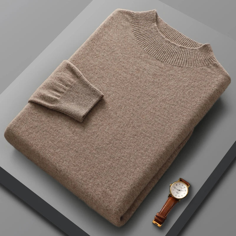 Folded beige sweater on a gray surface with a watch beside it