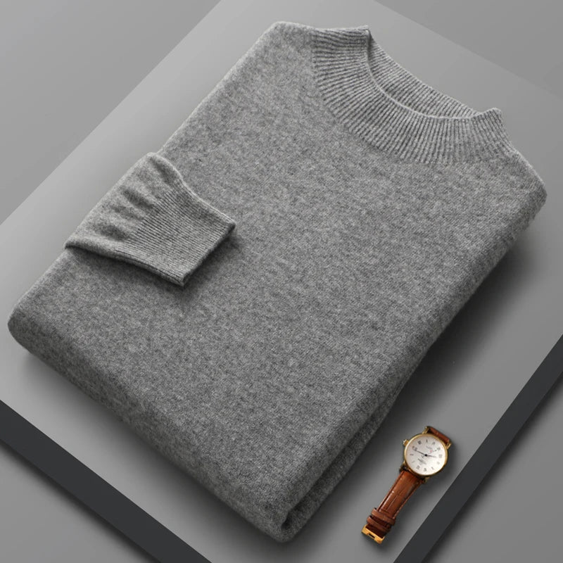 Folded gray sweater on a gray surface with a brown watch.