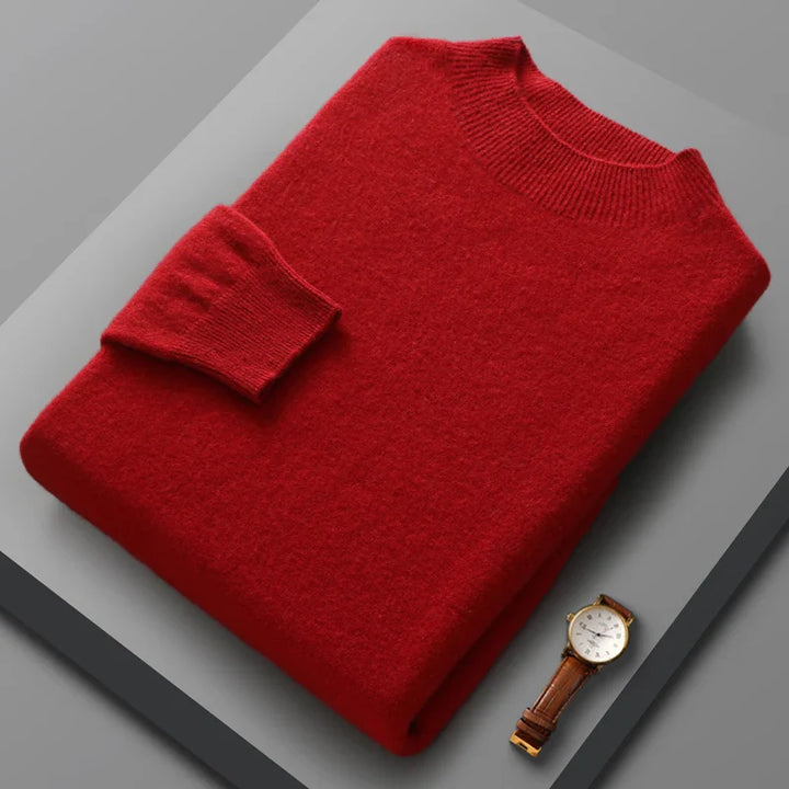 Folded red sweater on a gray surface with a gold watch.