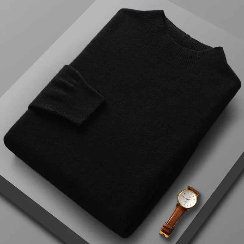 Black sweater on a gray surface with a watch beside it