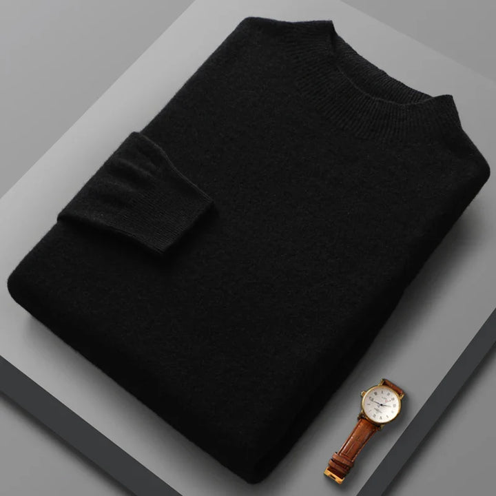 Black sweater on a gray surface with a watch beside it