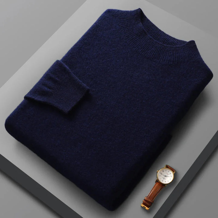 Folded navy blue sweater on a gray surface with a gold watch.