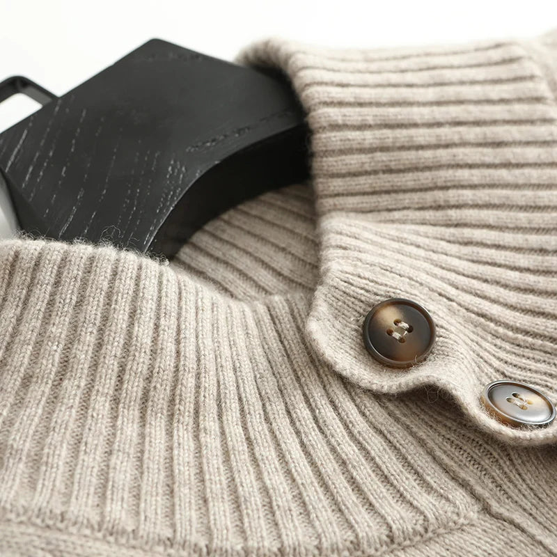 Close-up of a beige ribbed sweater with buttons and a black leather item.