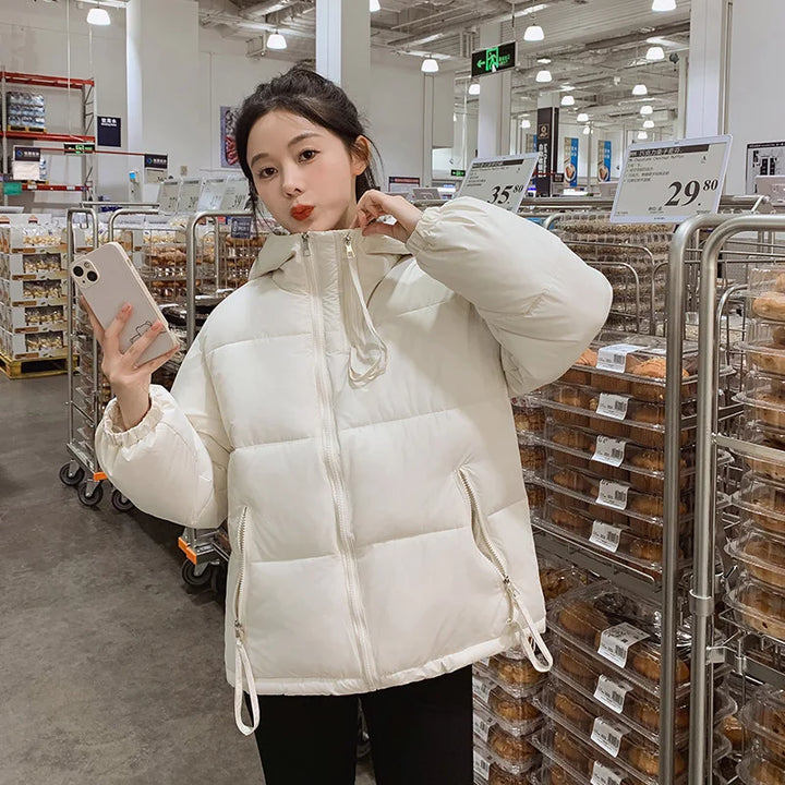 Person wearing a white puffer jacket in a store setting with shelves and products in the background.