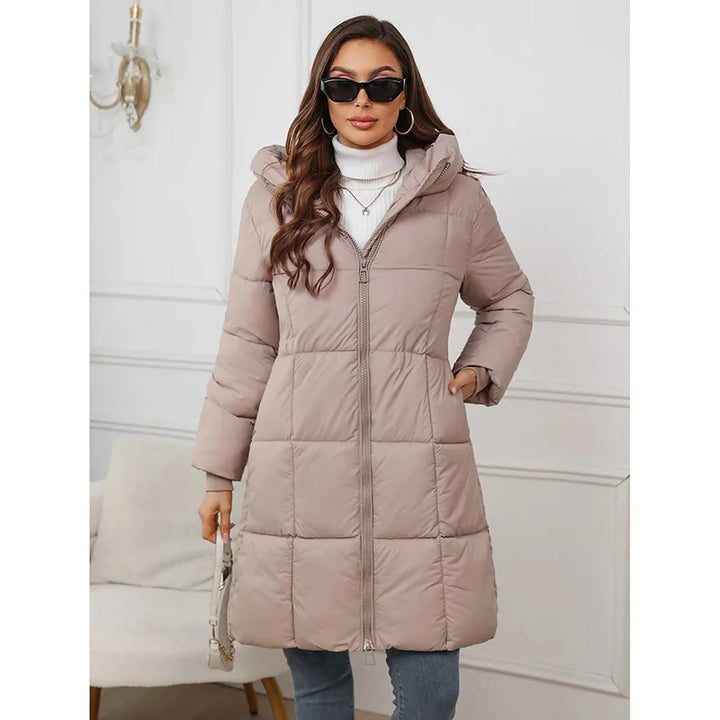 Woman wearing a long beige puffer coat in a neutral setting