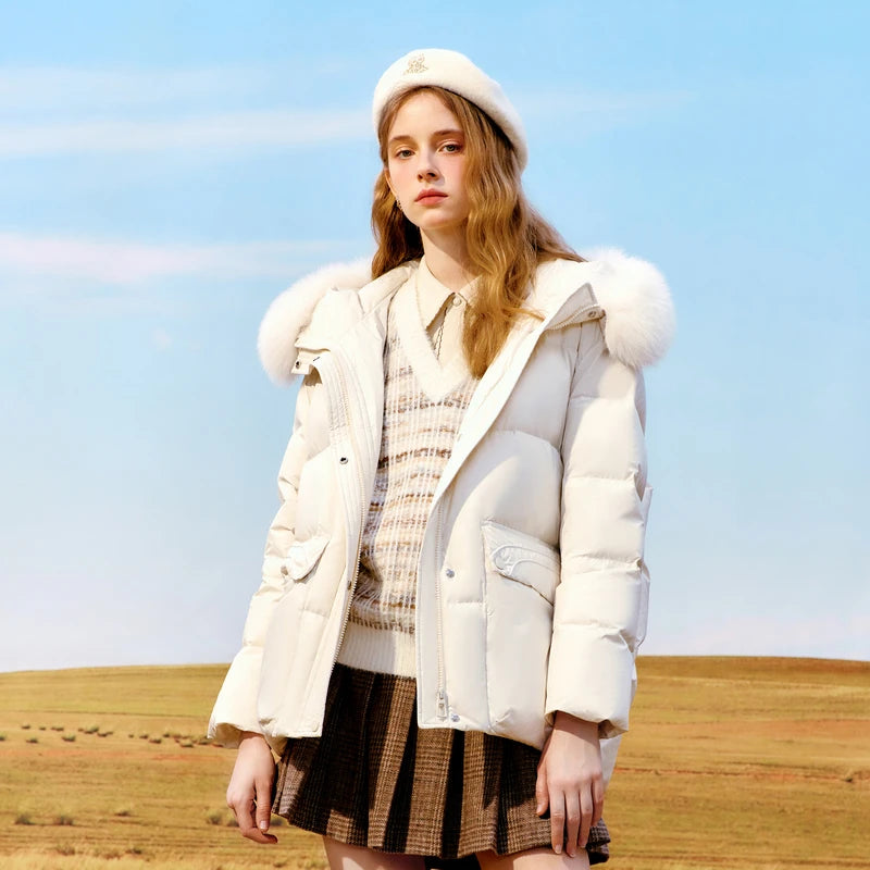 Woman wearing a white puffer jacket with fur trim in an open field.