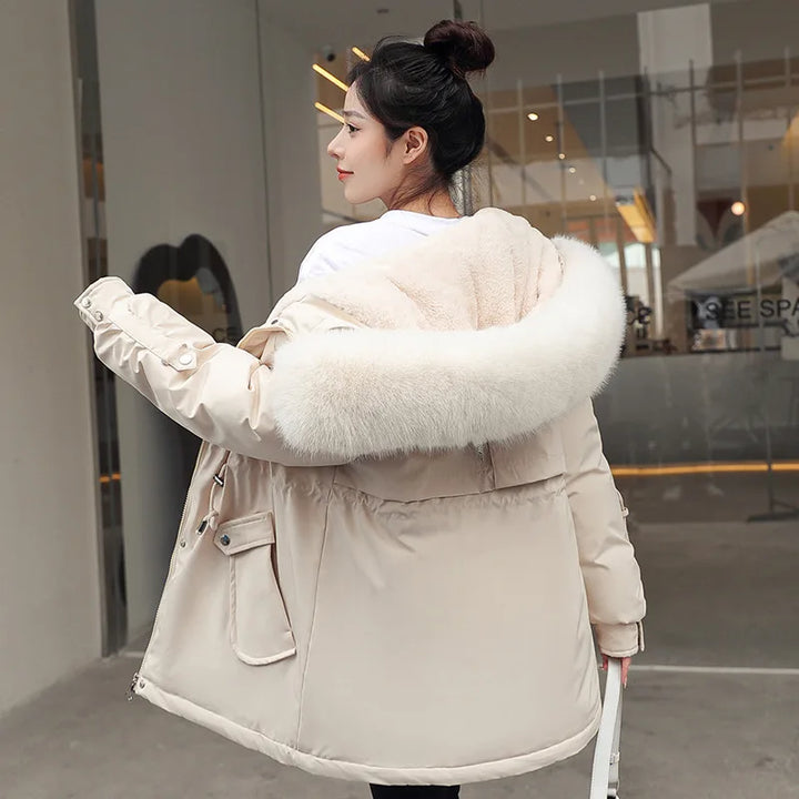 Woman wearing a beige winter coat with a fur-lined hood in an urban setting