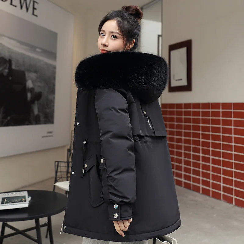 Woman wearing a black winter coat with a fur-lined hood in an indoor setting.