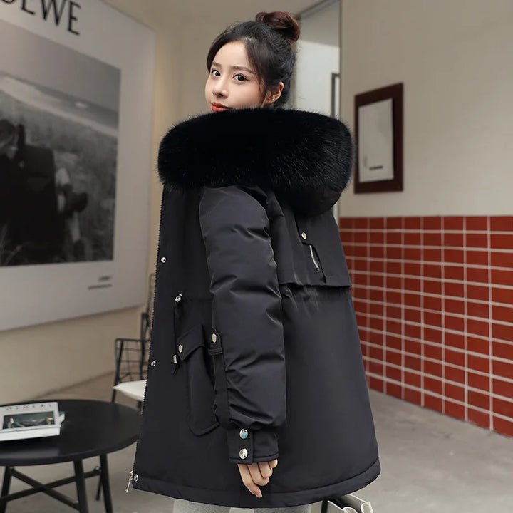 Woman wearing a black winter coat with a fur-lined hood in an indoor setting.