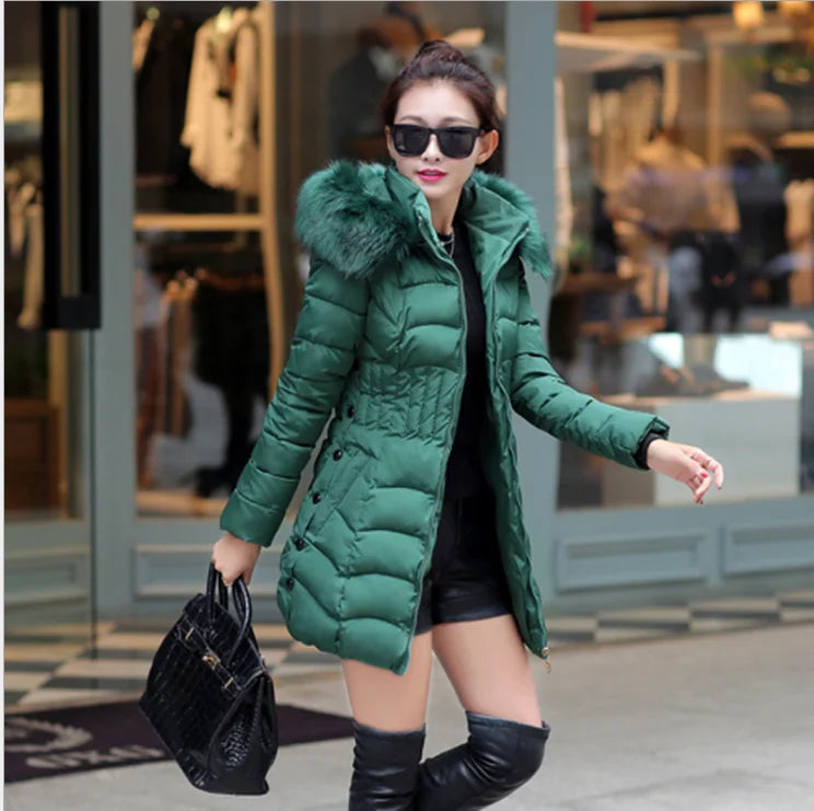 Woman wearing a green puffer coat with a fur-lined hood in an indoor setting.