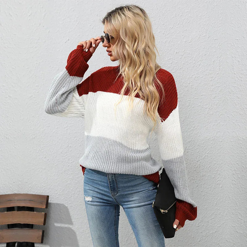 Woman wearing a colorful sweater and jeans against a plain background