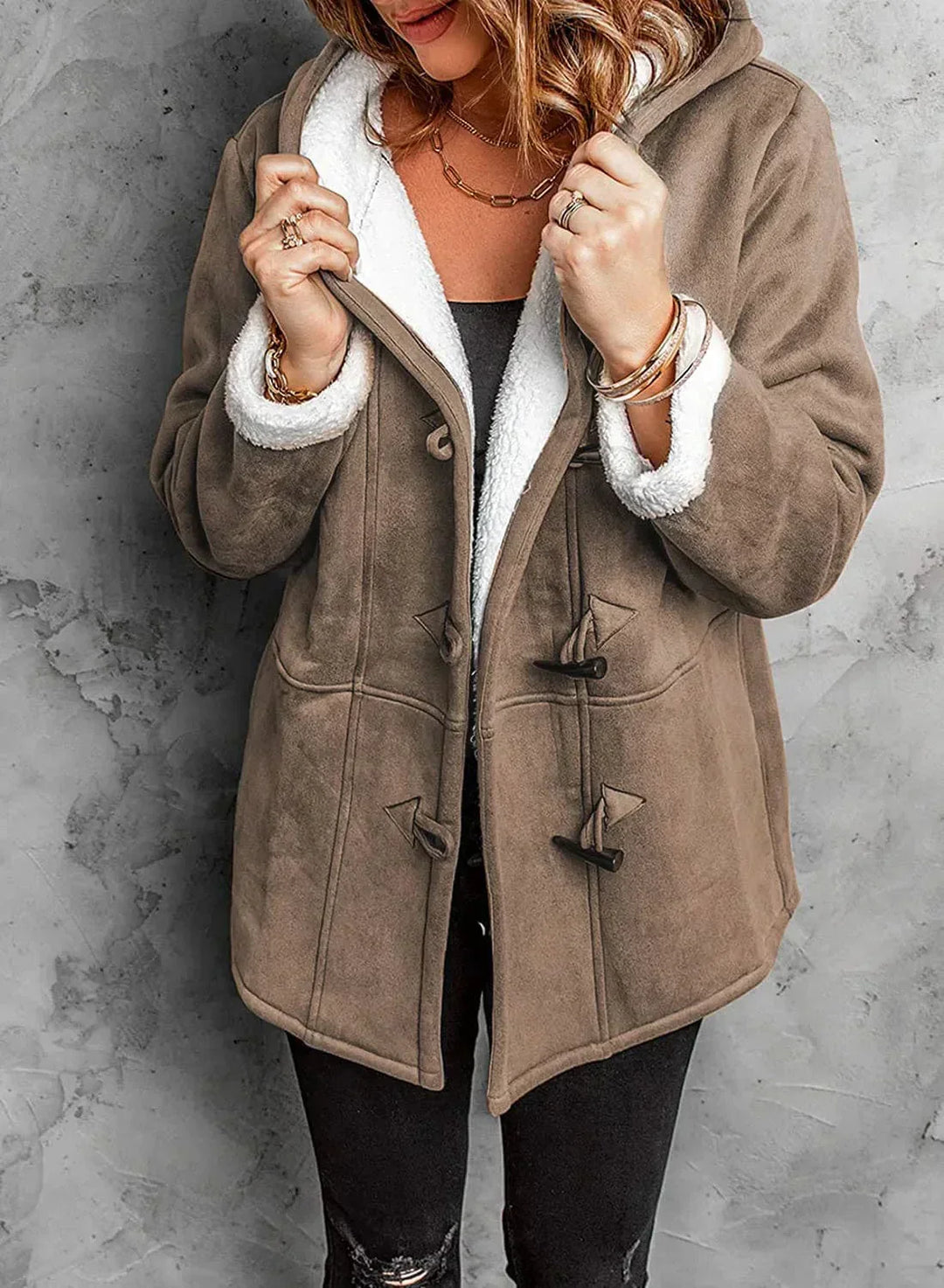 Brown coat with white fur lining worn by a person against a gray background