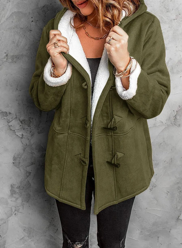 Person wearing a green coat with white fur lining against a gray background