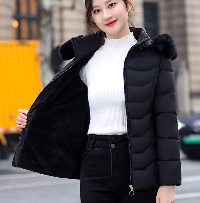 Woman wearing a black puffer jacket with fur hood on a city street.