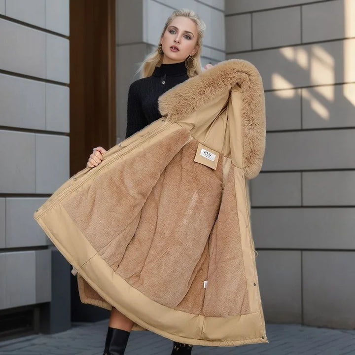 Woman holding a beige coat with fur trim against a tiled wall.