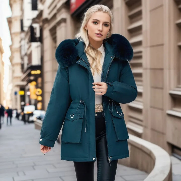Woman wearing a teal coat with fur hood on a city street