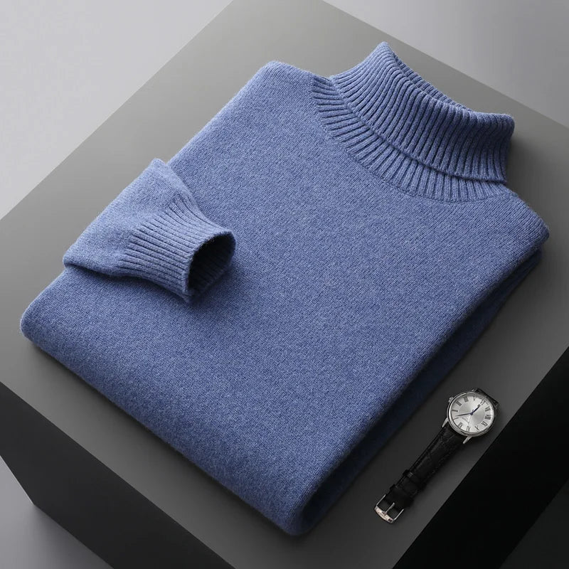 Folded blue sweater on a gray surface with a watch beside it