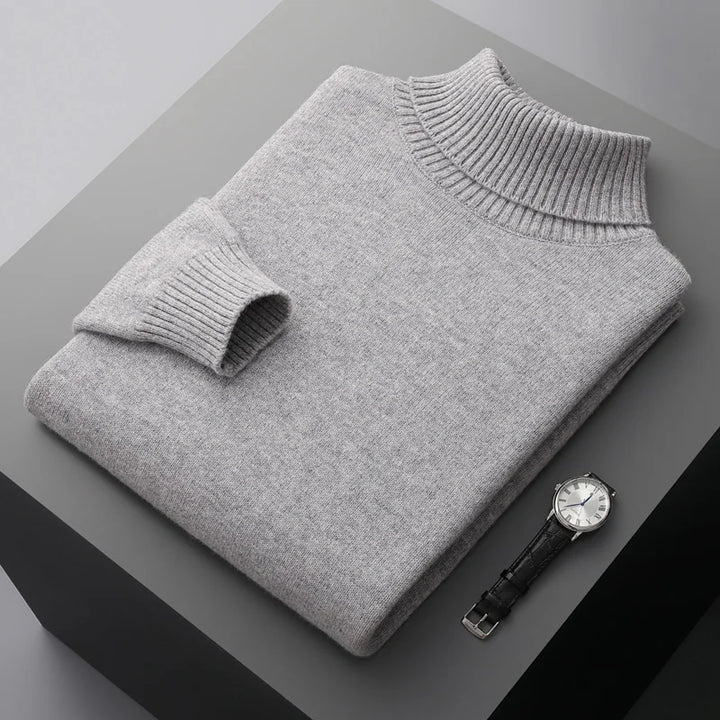 Folded gray sweater on a dark surface with a watch beside it