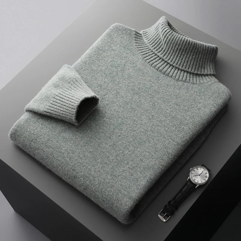 Folded gray sweater on a dark surface with a watch beside it