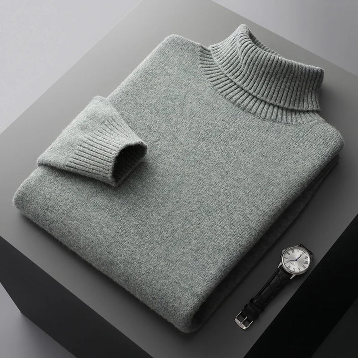 Folded gray sweater on a dark surface with a watch beside it