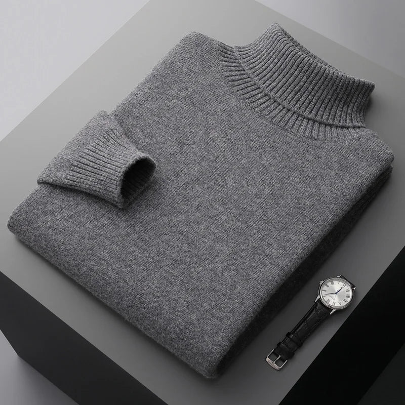 Folded gray sweater on a dark surface with a watch beside it