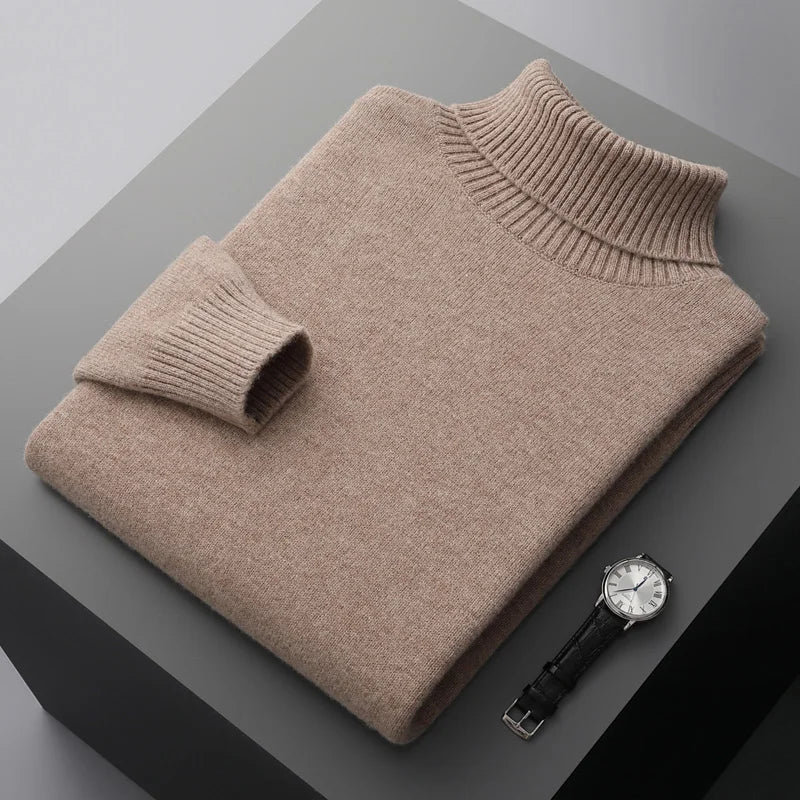 Folded beige sweater on a gray surface with a watch beside it