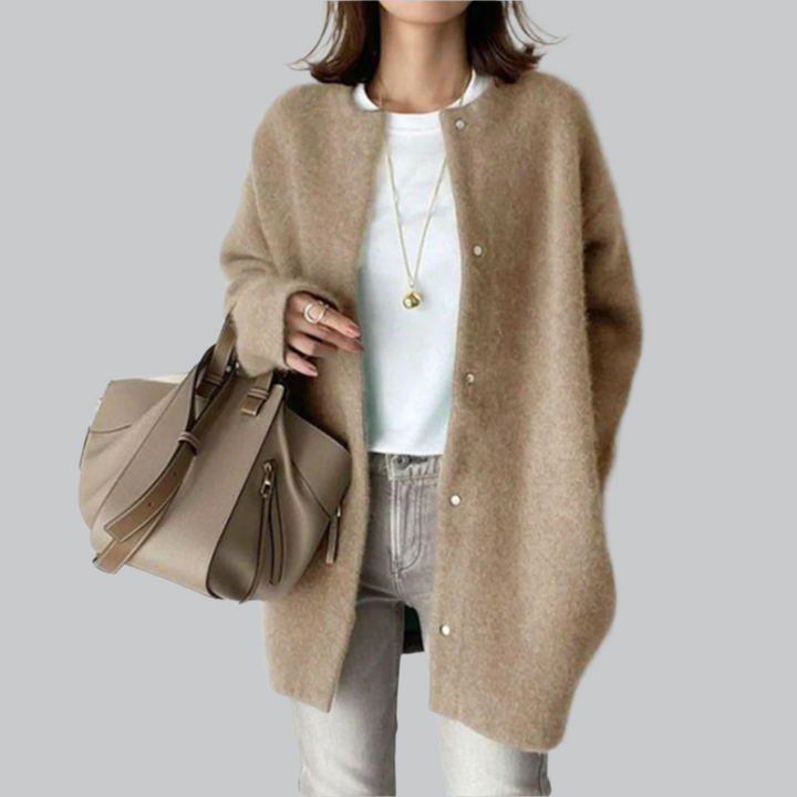 Person wearing a beige cardigan holding a matching handbag on a plain background