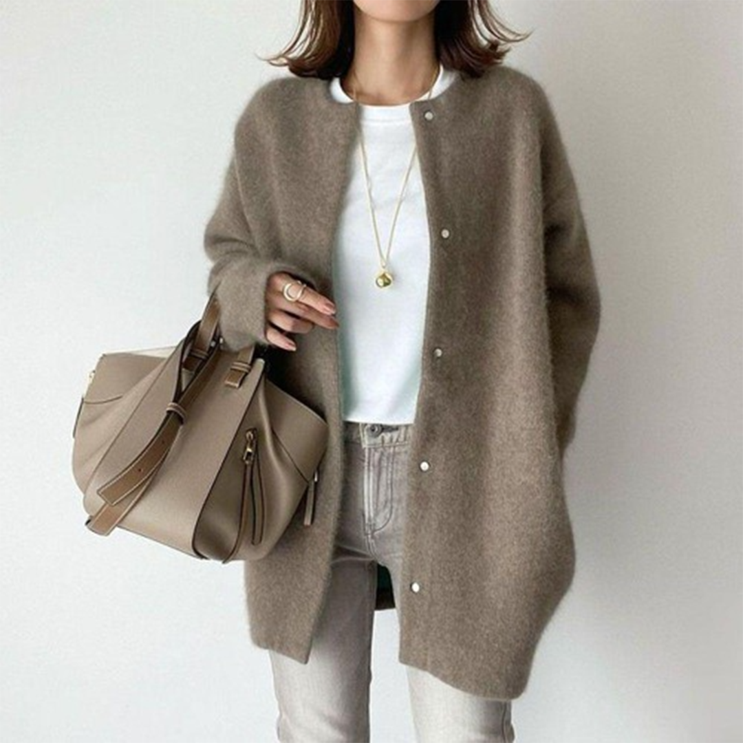 Person wearing a brown cardigan with a beige handbag on a white background