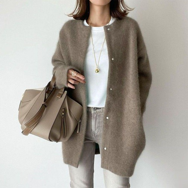 Person wearing a brown cardigan with a beige handbag on a white background