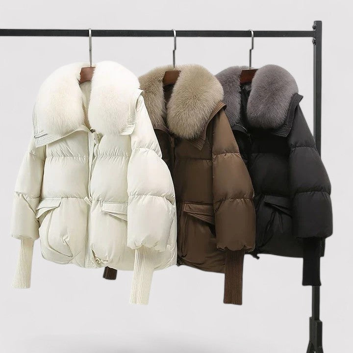 Three puffer jackets with fur hoods on a rack against a white background