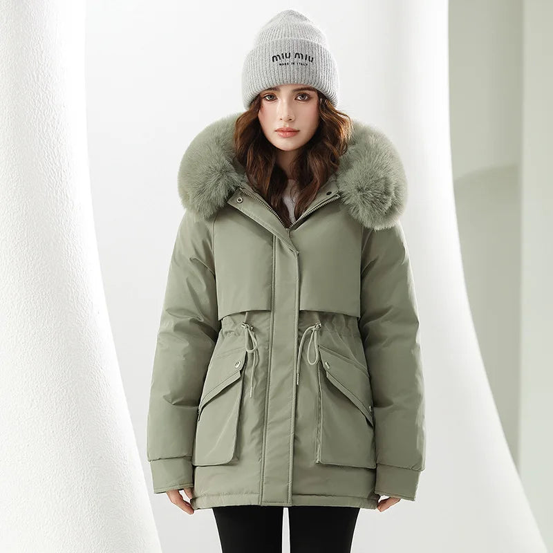 Woman wearing a green parka with fur hood and a gray beanie on a white background