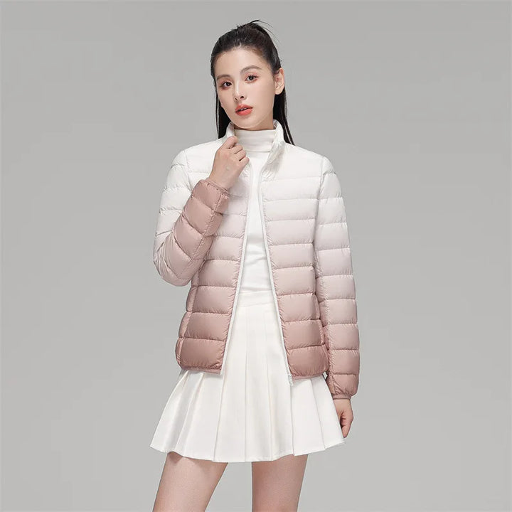 Person wearing a gradient white to pink puffer jacket on a gray background