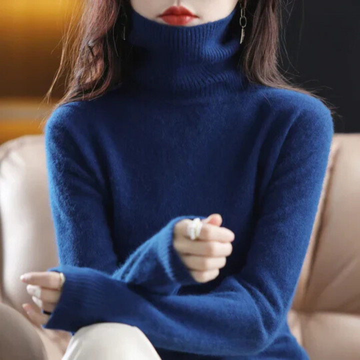 Person wearing a blue turtleneck sweater sitting on a beige couch.