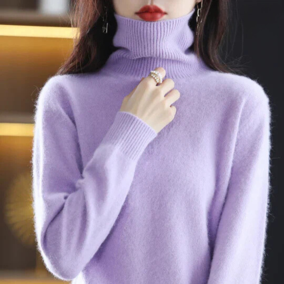 Person wearing a light purple turtleneck sweater with a blurred background