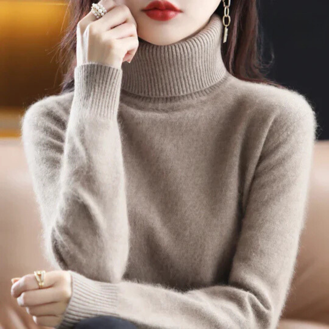 Person wearing a beige turtleneck sweater with a blurred background