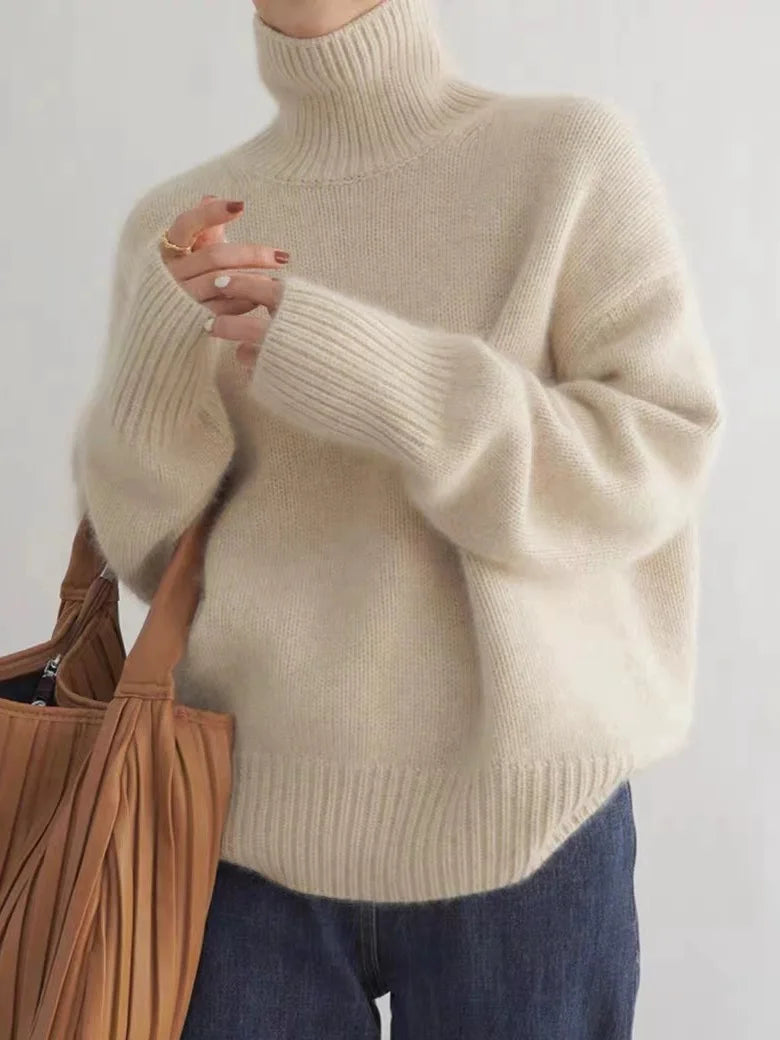 Person wearing a beige turtleneck sweater with a plain background
