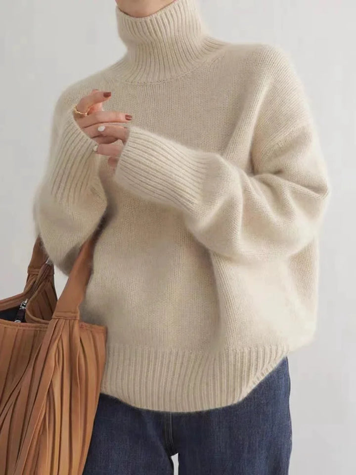 Person wearing a beige turtleneck sweater with a plain background