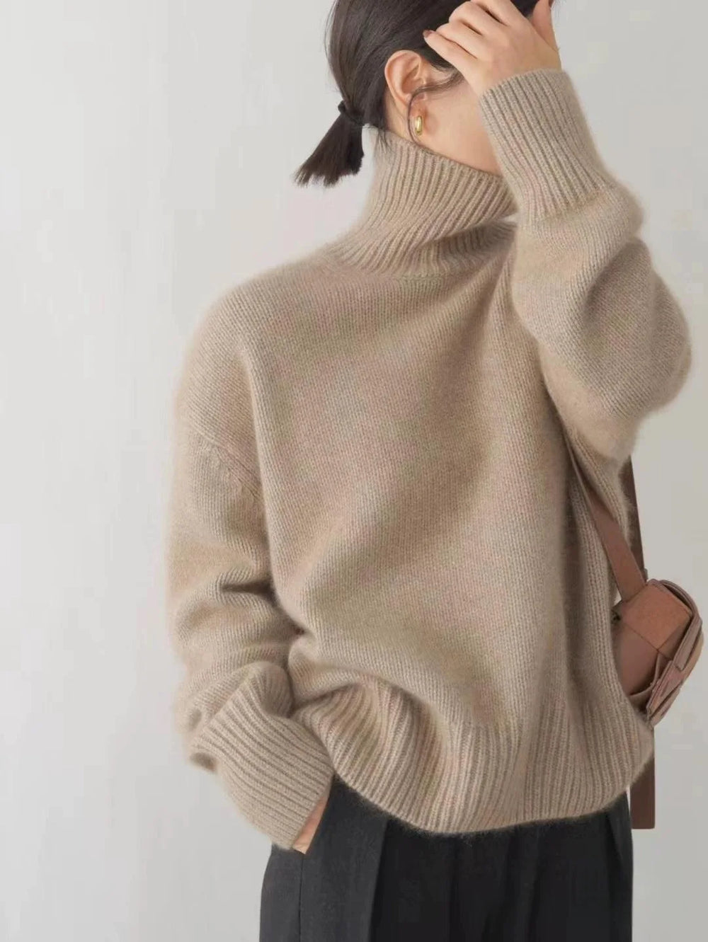 Person wearing a beige sweater against a plain background