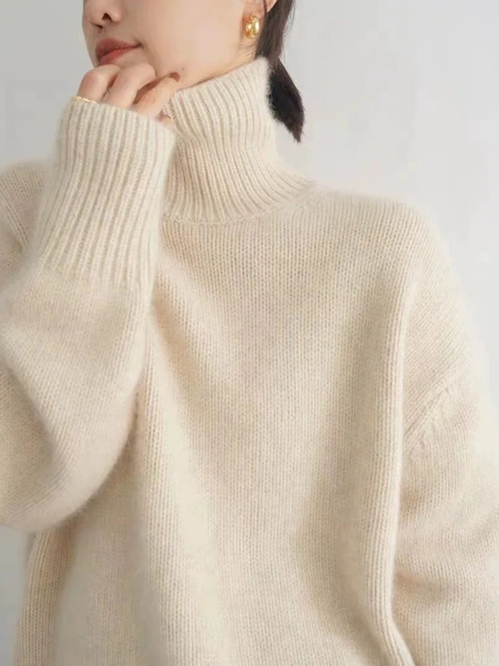 Person wearing a beige turtleneck sweater against a plain background
