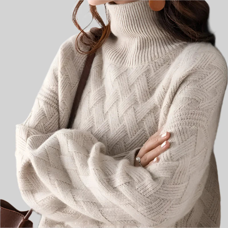 Close-up of a person wearing a beige turtleneck sweater against a plain background