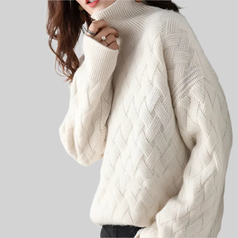 White cable knit sweater worn by a person on a light gray background