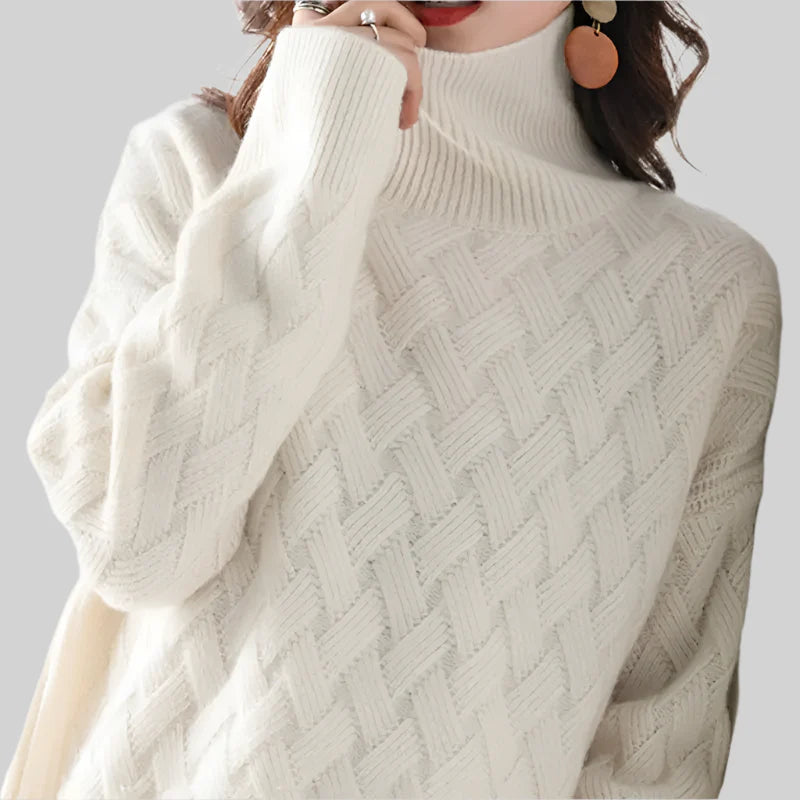 Close-up of a person wearing a white cable knit sweater against a gray background
