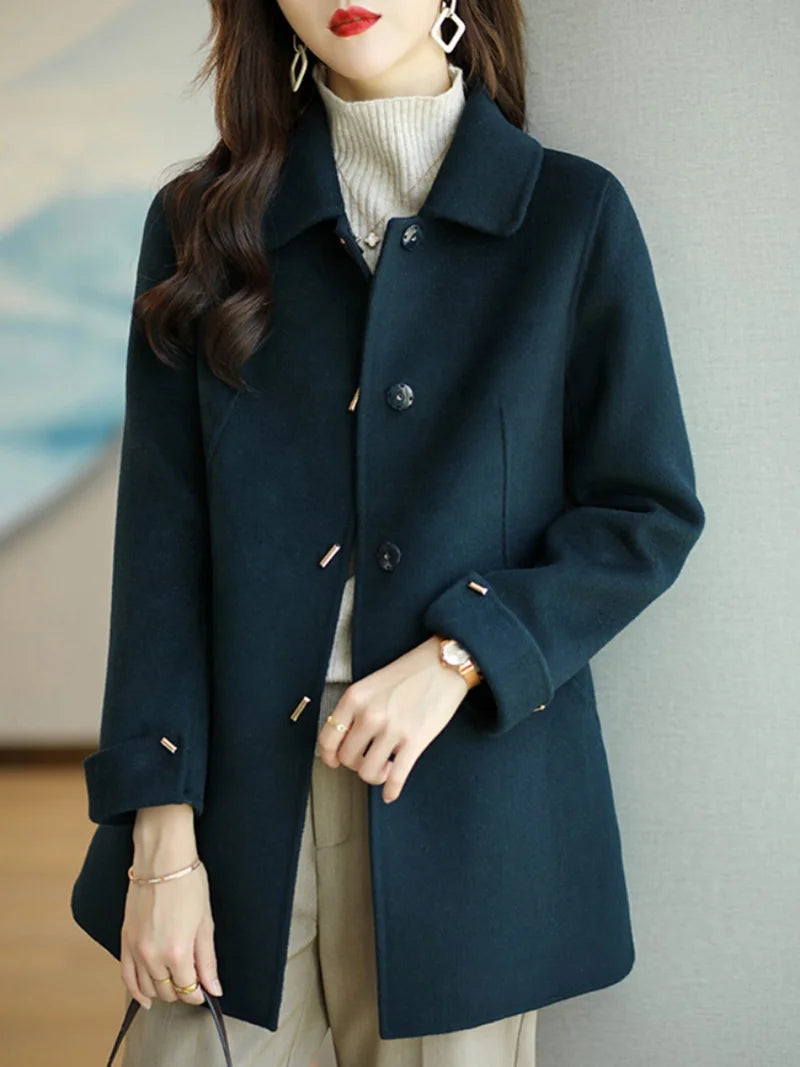 Woman wearing a dark blue coat against a neutral background