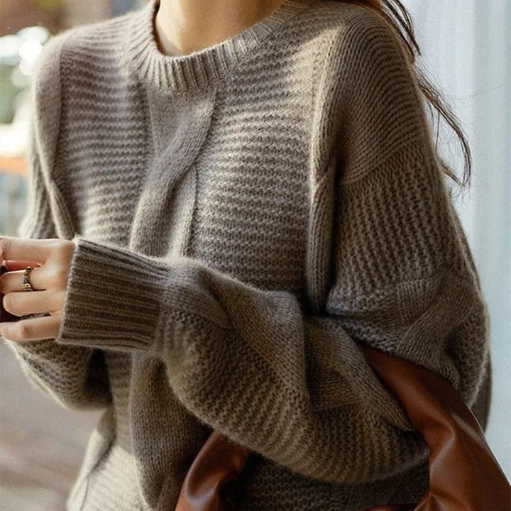 Close-up of a person wearing a brown knitted sweater with a blurred background